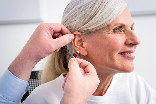 Ältere Frau erhält ein modernes Hörgerät zur Hörverbesserung durch einen Akustiker.